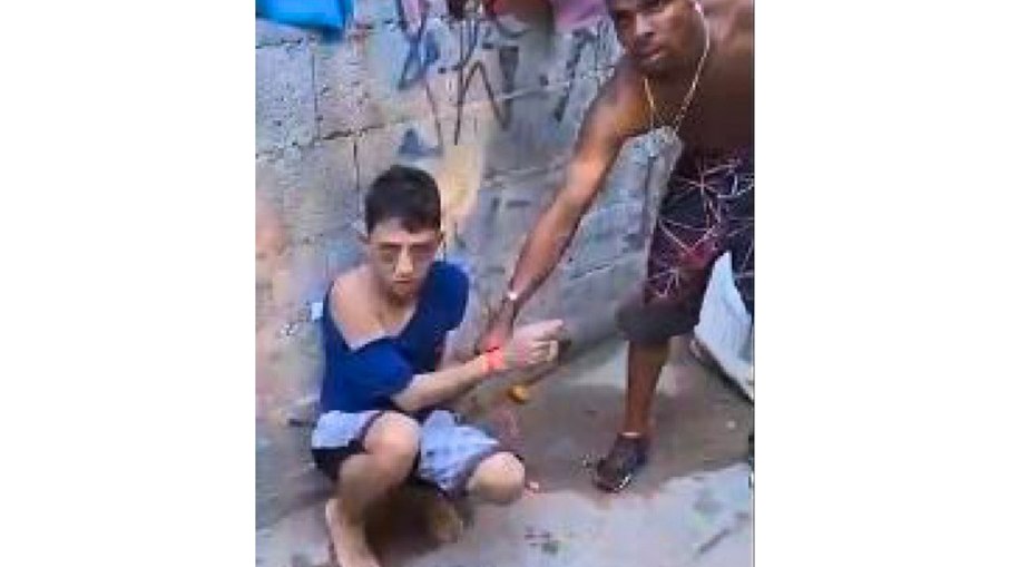 O fim de um informante: Roberto Hipólito, o "Zóio de Gato", aparece rendido e machucado na Favela da Funerária. Na imagem, Alisson Alexandre Borges, o "TK", segura seu braço momentos antes da execução decretada pelo Tribunal do Crime